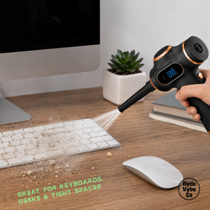 Person using a handheld vacuum cleaner on a desk with keyboard and mouse.